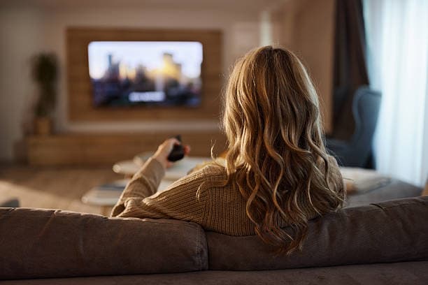 Viewer setting up and streaming IPTV on television with remote control in living room